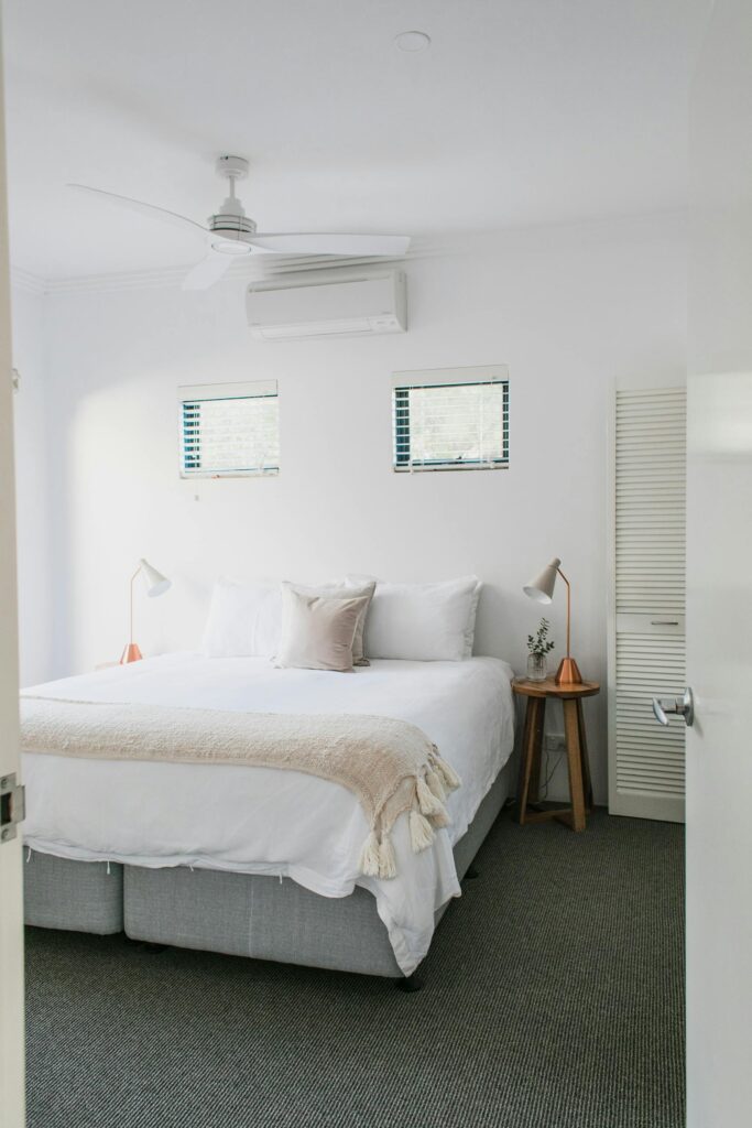 A modern white bedroom with soft textiles, cozy pillows, and contemporary decor for a peaceful retreat.